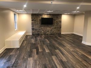 Stone veneer TV area, vinyl plank flooring, and custom built in bench with storage