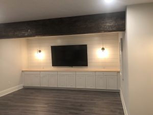 TV area built-ins with ship lap wall and scone lights plus hand hewn barn beam