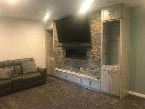 TV area cabinetry with ledgestone tile and gas fireplace